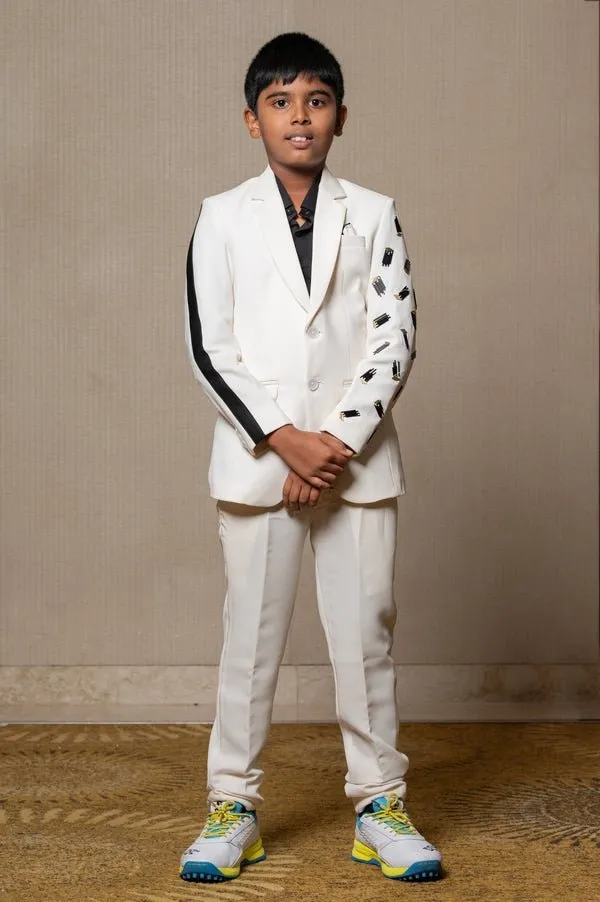 Modern off-white suit with Blackaccents and stylish embroidered sleeve detail, paired with trendy sneakers for a unique, contemporary look