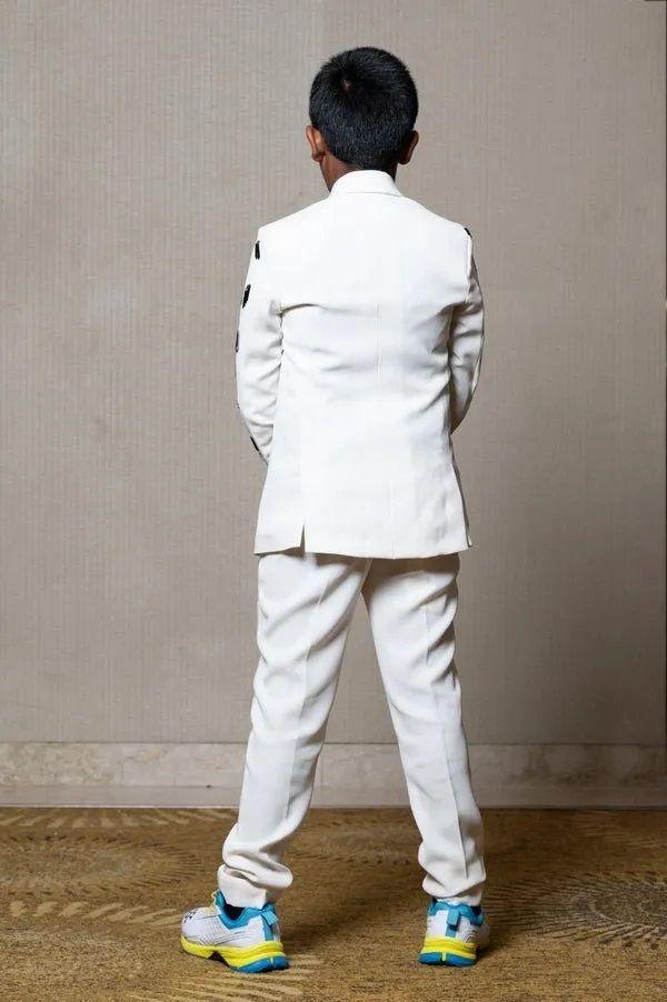 Modern off-white suit with Blackaccents and stylish embroidered sleeve detail, paired with trendy sneakers for a unique, contemporary look